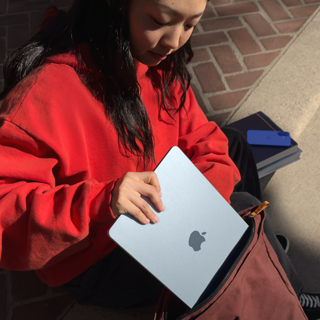 Eine Studentin legt ein MacBook Air in den Rucksack